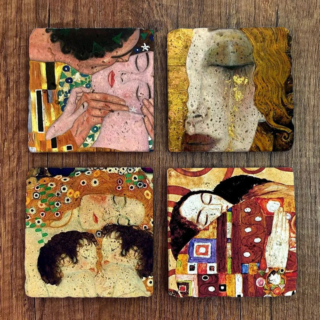 Four artistic coasters with Klimt-style designs on a wooden surface