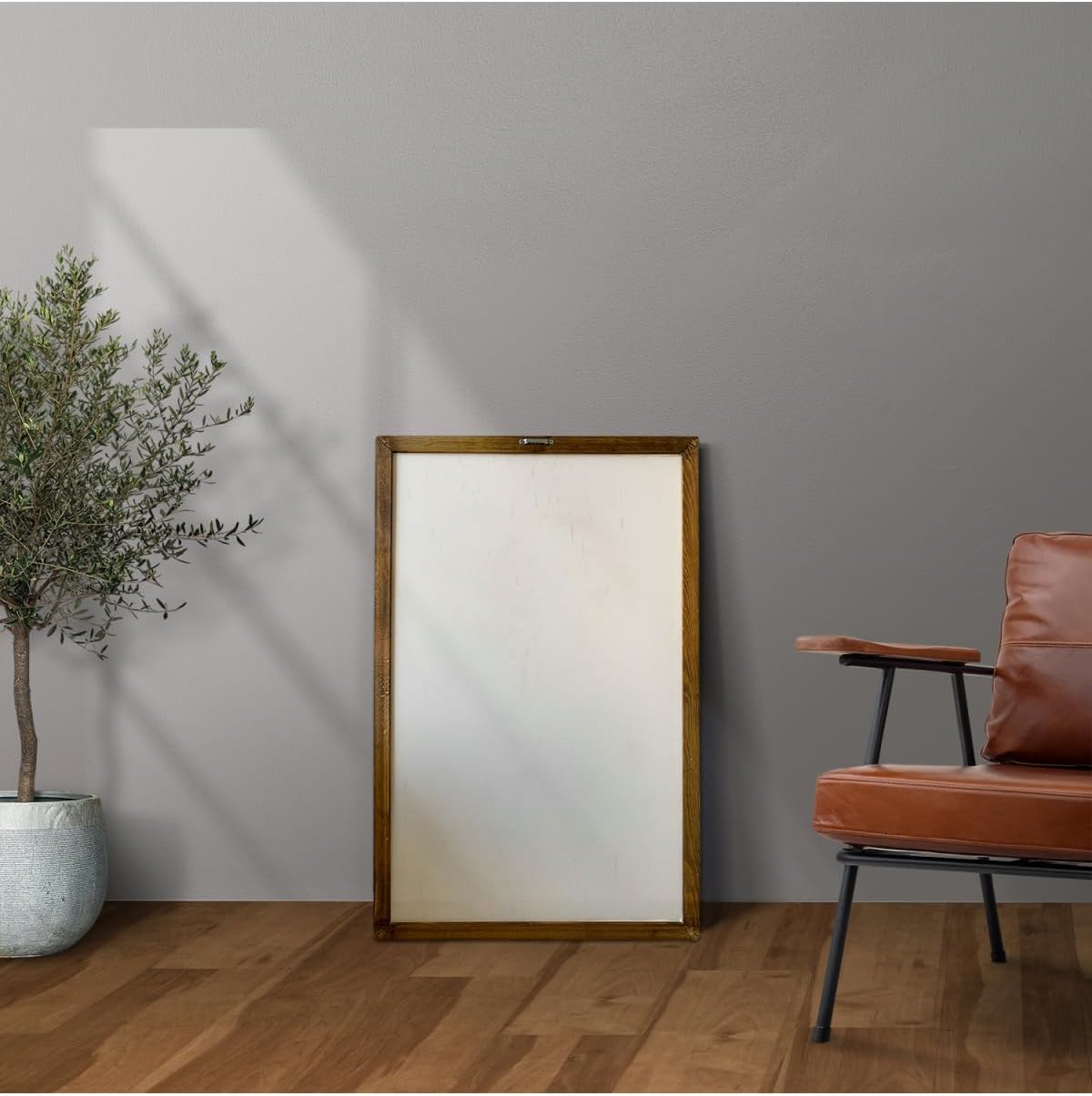 Room interior with a large mirror, plant, and brown chair against a gray wall.