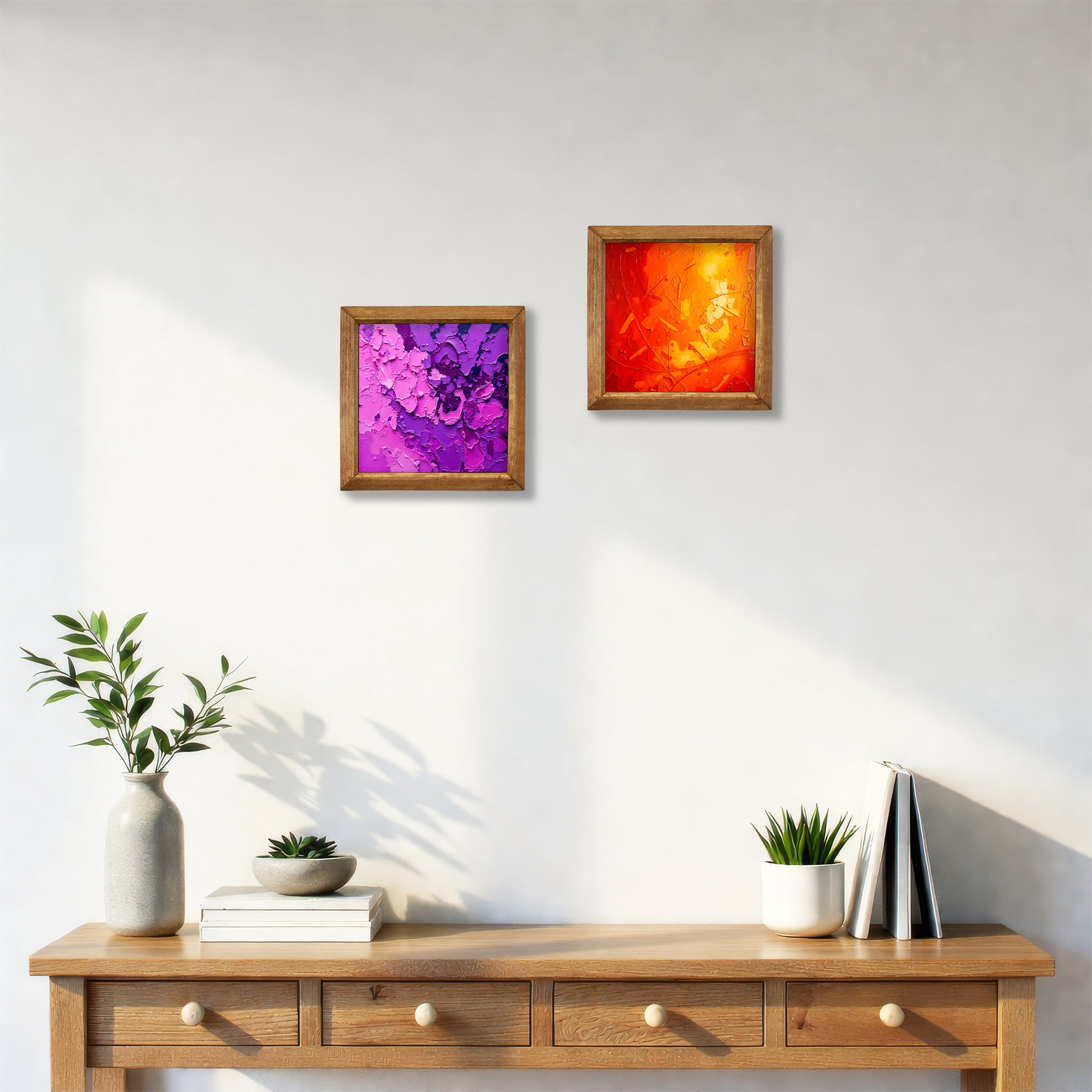 Two framed abstract paintings on a wall above a wooden console table with decorative items.