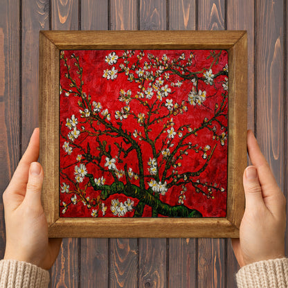 Framed artwork resembling 'Blossoming Almond Tree' by Van Gogh held against a wooden background.