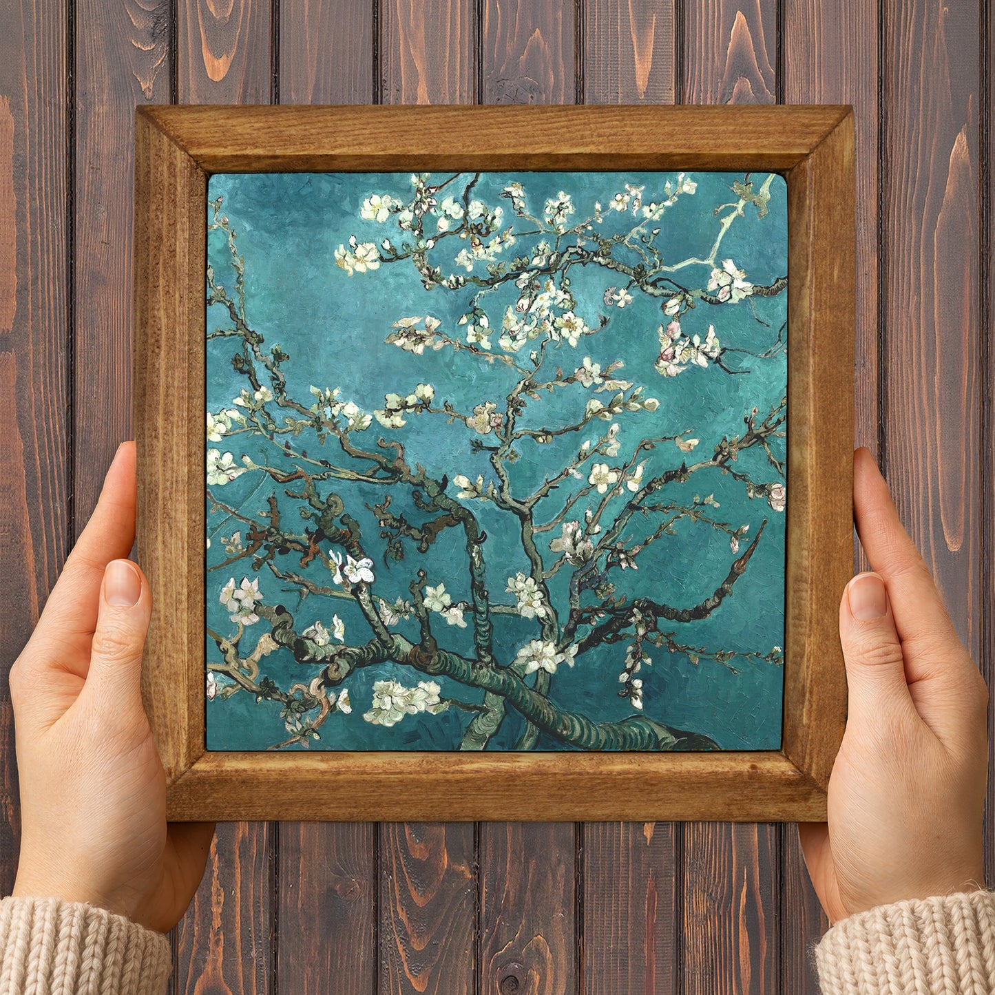 Framed artwork of a floral branch against a wooden background