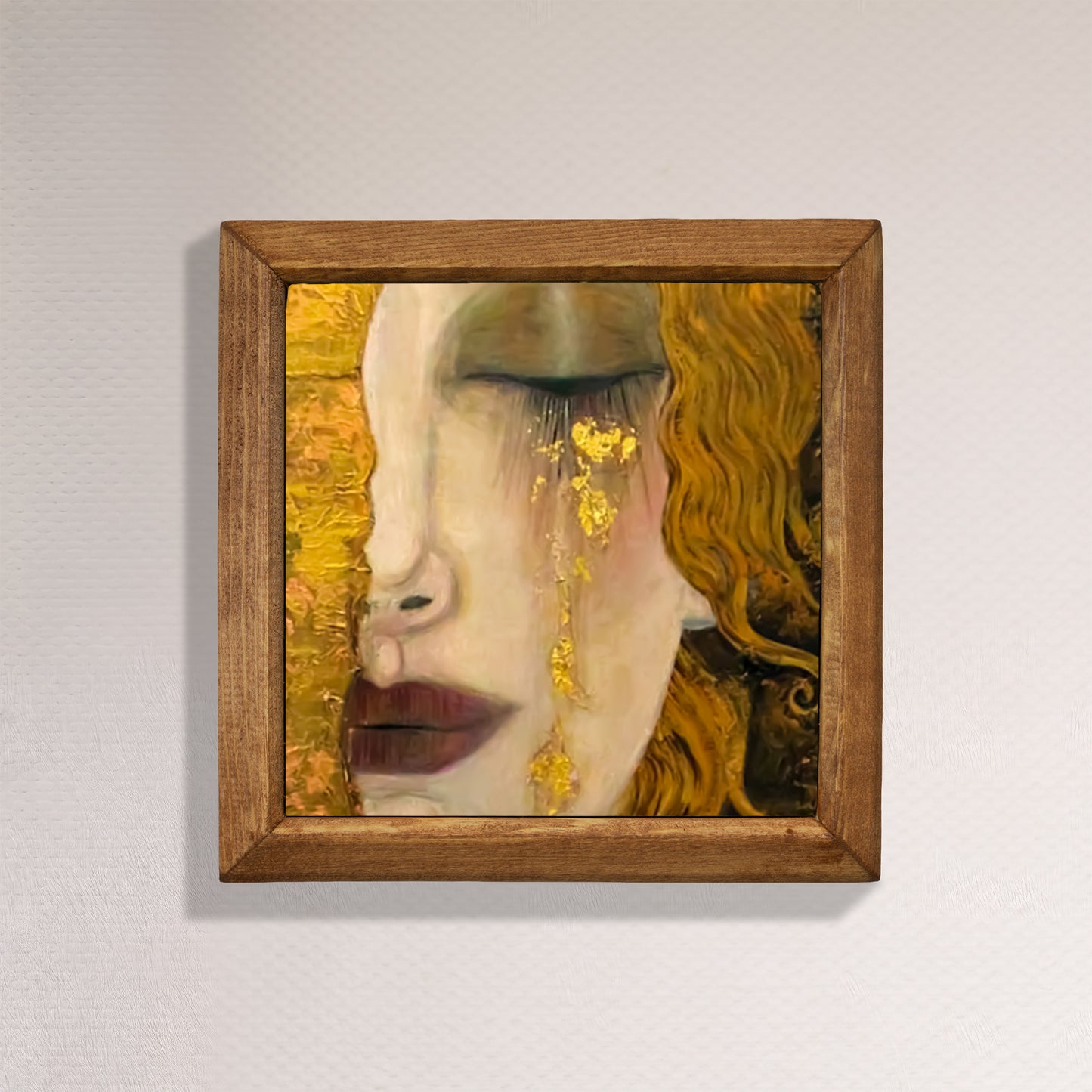 Framed artwork of a face with gold accents on a plain wall