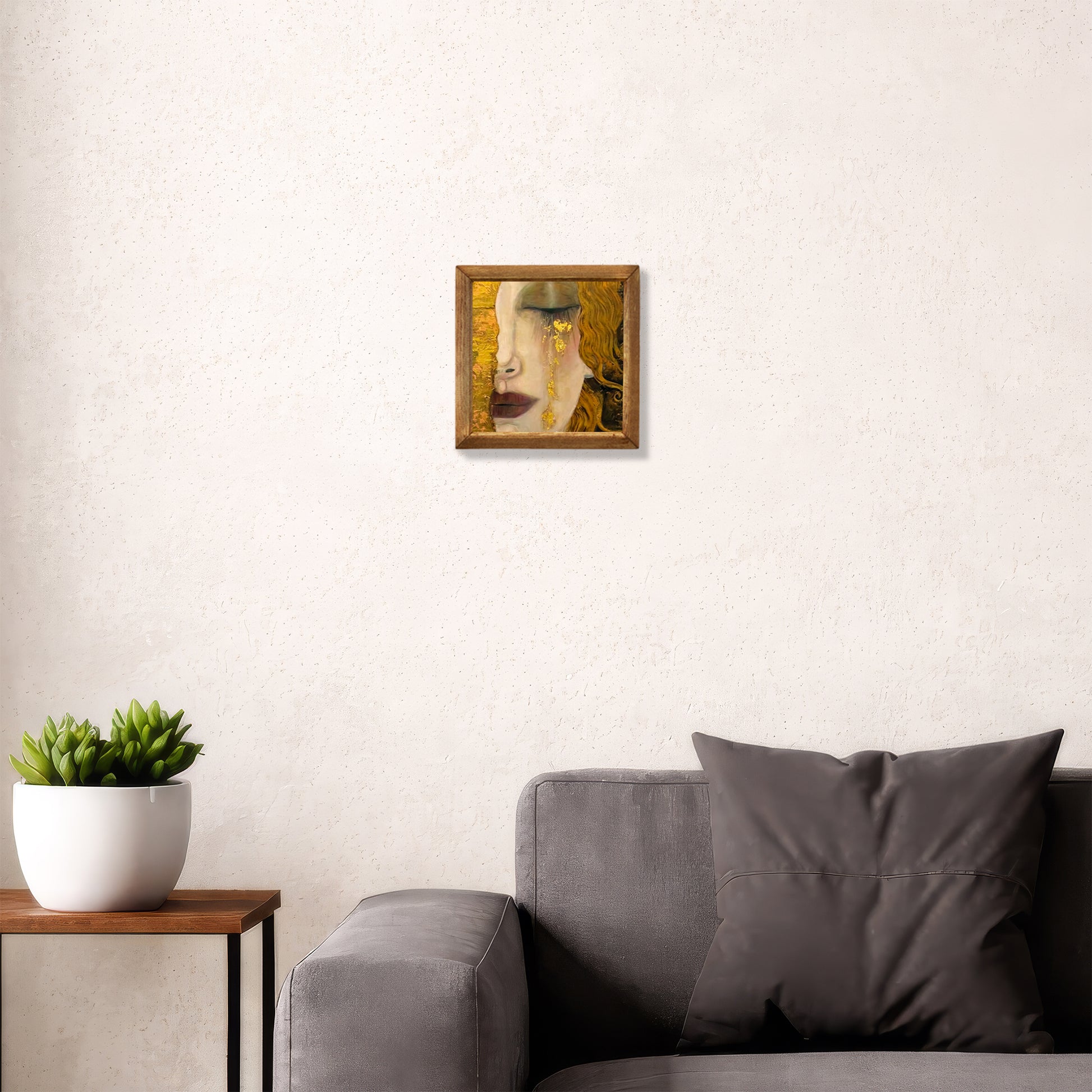 Gray sofa with a plant and a framed picture on a white wall
