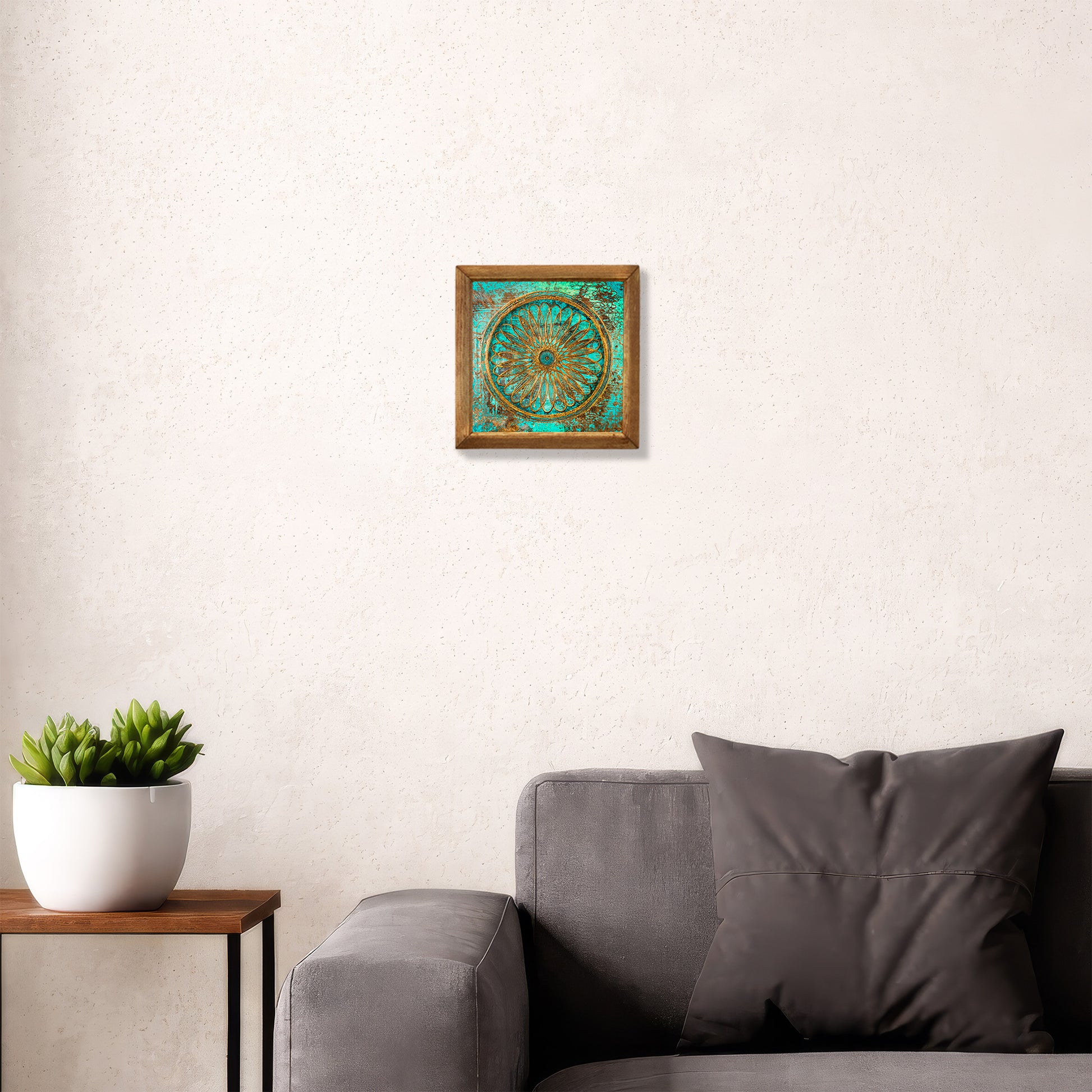 Framed artwork on a wall above a gray sofa with a plant beside it.