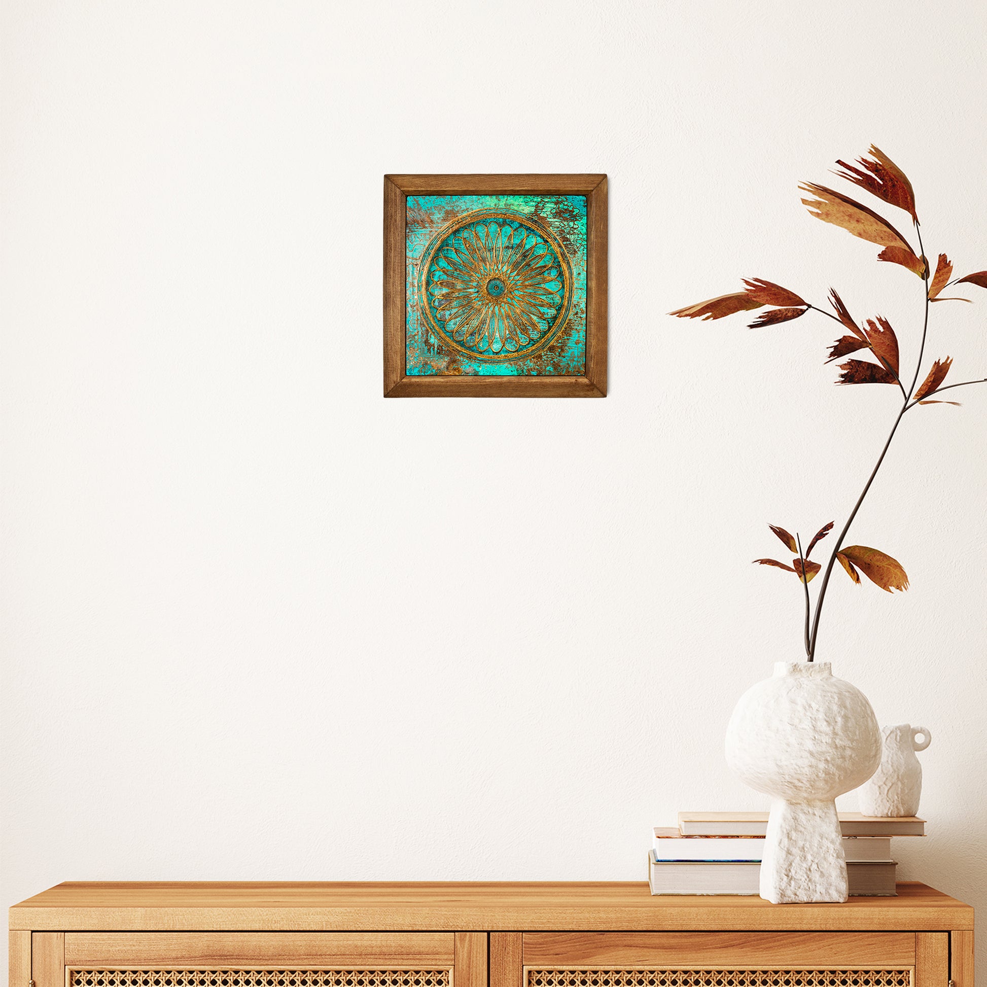 Decorative wall art piece on a white wall above a wooden console table with a vase and books.