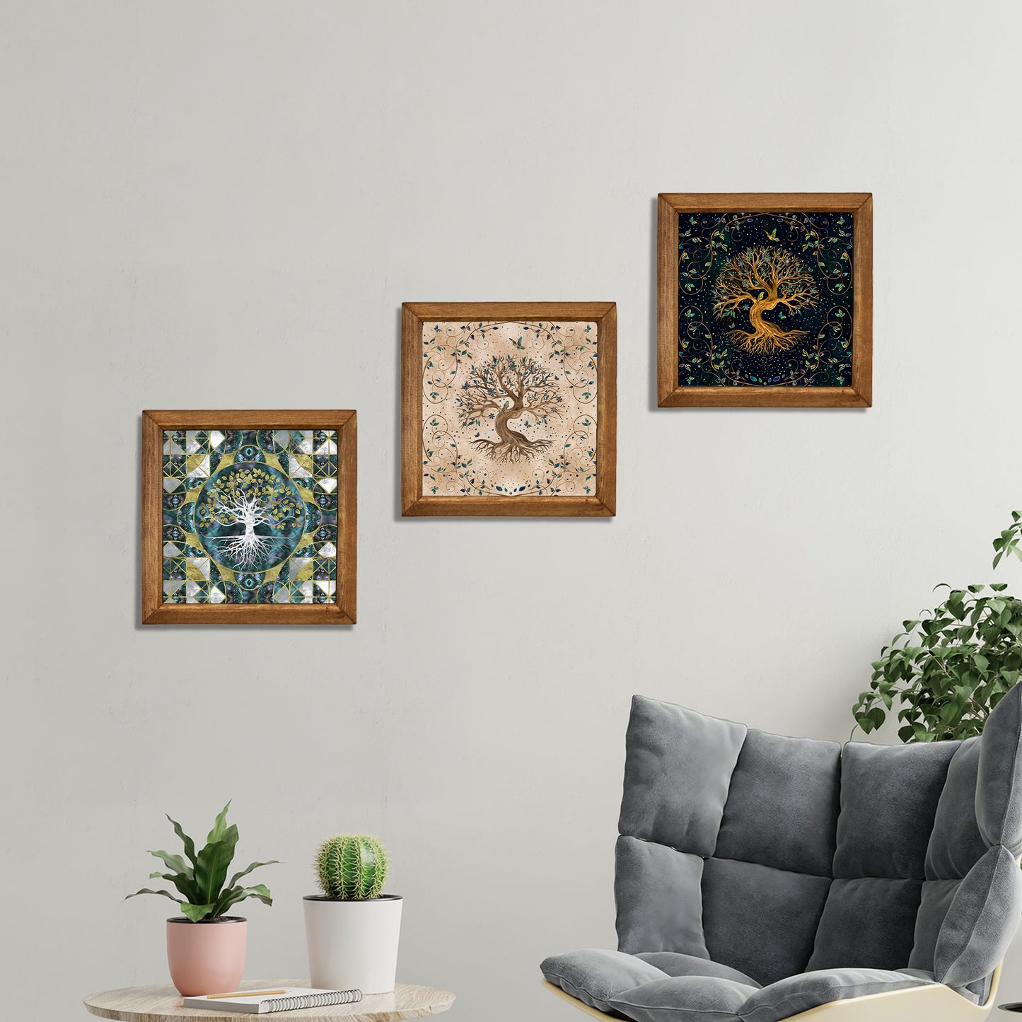 Three framed artworks on a wall above a gray sofa with plants.