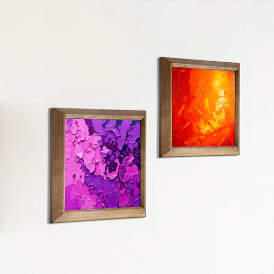 Two framed abstract paintings on a white wall, one with purple and pink colors and the other with orange and red.